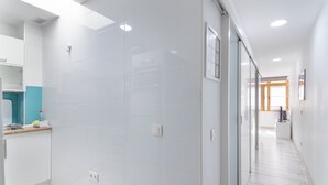 Una cocina moderna con azulejos blancos, encimera de madera y vistas al área de estar contigua.