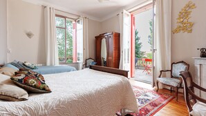 Een slaapkamer met een bed, een houten kast, een stoel en uitzicht op buiten.