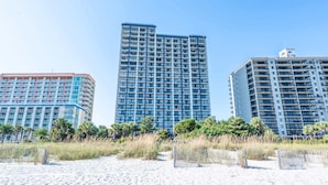 Un hôtel situé en bord de mer, composé de plusieurs immeubles de grande hauteur, doté de balcons et offrant une vue sur un ciel dégagé.