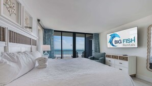 Une chambre d’hôtel avec un grand lit, une télévision, une vue sur la mer et une enseigne « Big Fish Rentals ».