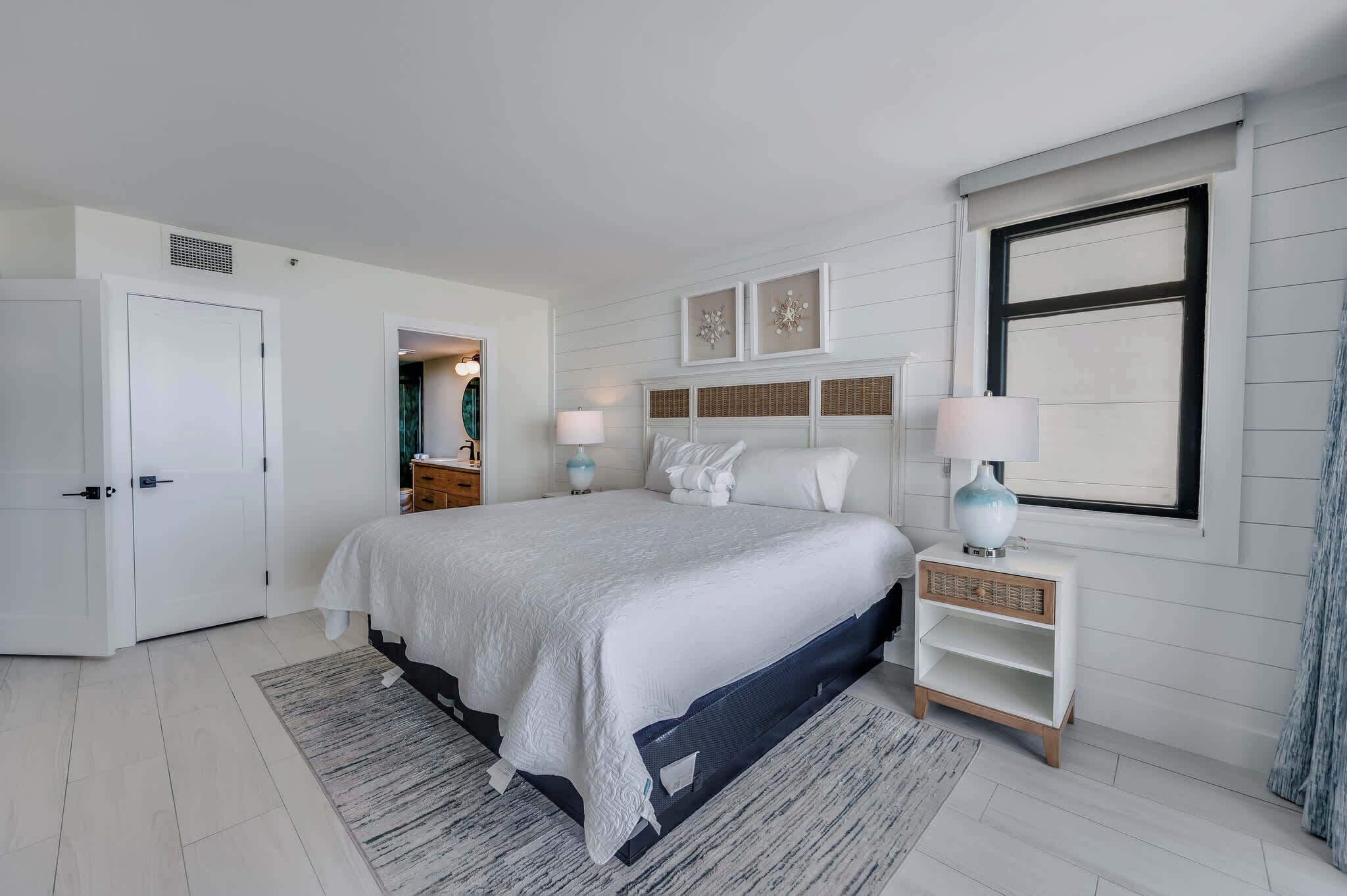 A bedroom with a bed, bedside tables, a wardrobe, and a window.