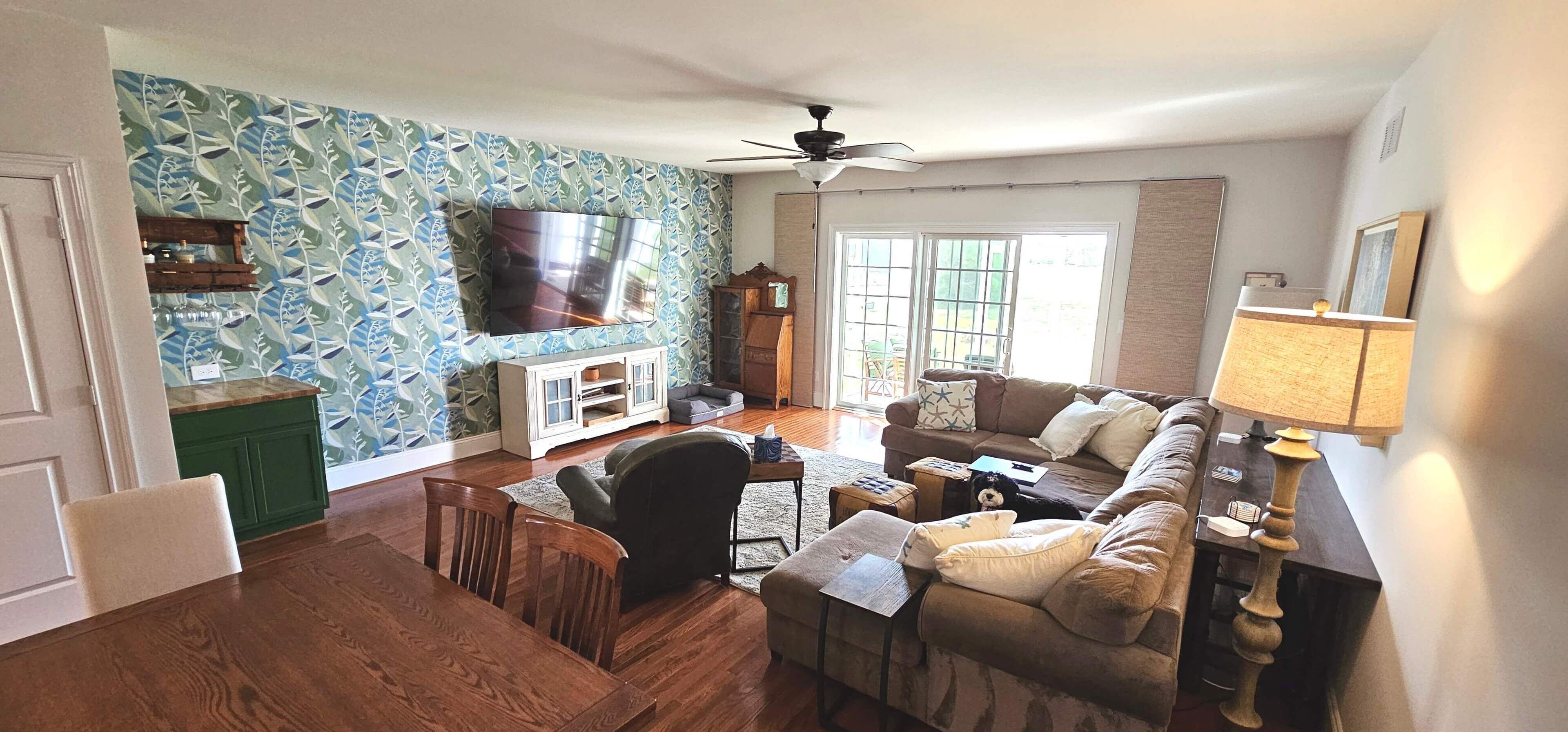 A living room with a TV, sofa, chairs, and a wooden cabinet.