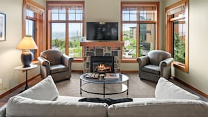 Una sala de estar con chimenea, dos sillones de cuero, un sofá, una mesa de centro y un televisor.