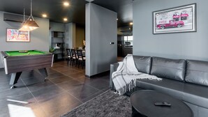 Una sala de estar moderna con mesa de billar, sofá y comedor.