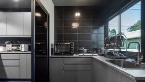 Una cocina moderna con armarios grises, horno empotrado, microondas y escurreplatos.