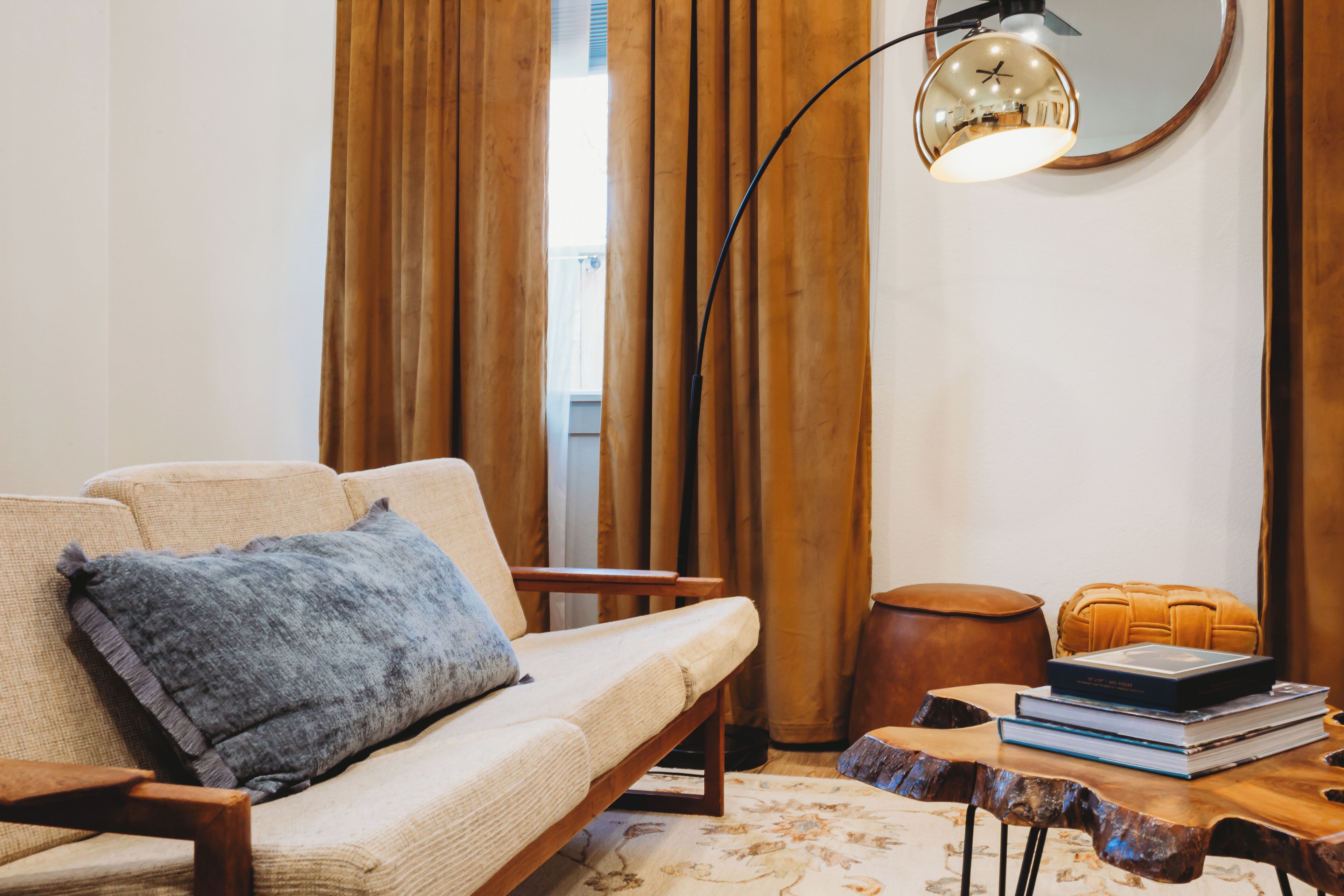 A cozy living room with a sofa, a coffee table, a lamp, and a window with curtains.