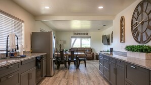 Una cocina con comedor, un reloj grande y un letrero que dice "FARMHOUSE".