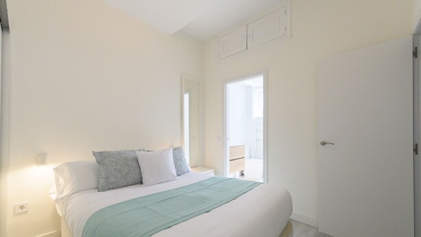 A bedroom with a bed, bedside tables, a nightstand, a window, and a door. - Monthly Rental in Madrid - Modern 1 bedroom flat (Madrid)