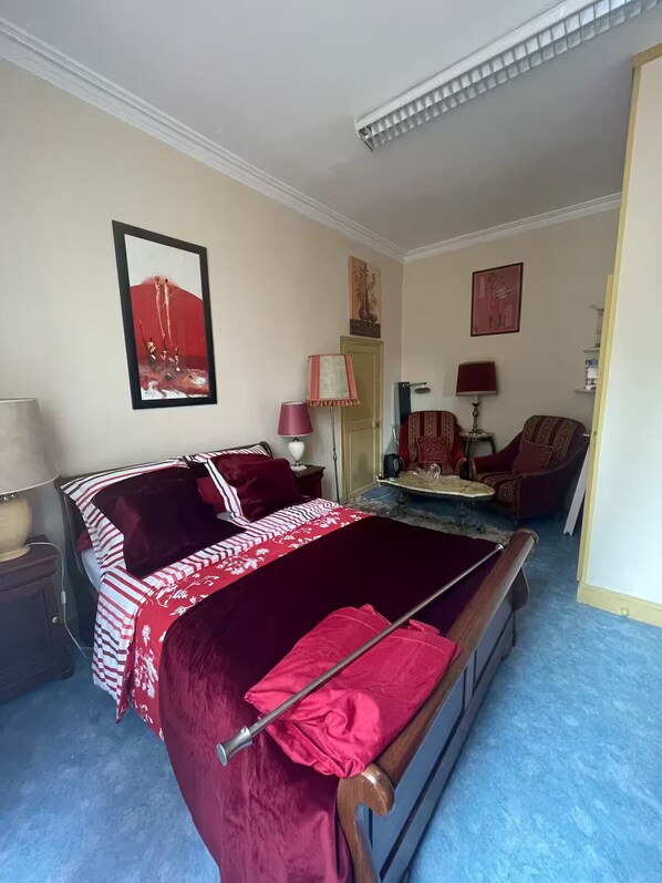 Une chambre à coucher avec un lit, une chaise, une lampe et un tableau au mur.
