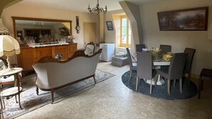 Un salón comedor amplio con techo alto, chimenea, una mesa con sillas y un gran ventanal que deja entrar luz natural.