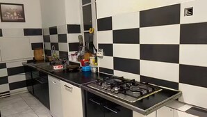 Una cocina con salpicadero a cuadros blanco y negro, una estufa a gas y diversos utensilios y electrodomésticos de cocina.
