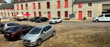 A building with multiple windows and a parking area with several cars.