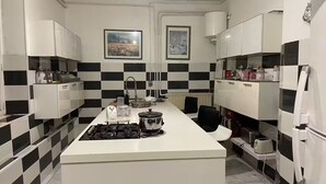 Una cocina moderna con una isla central, salpicadero blanco y negro a cuadros y armarios blancos.