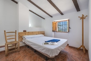 A bedroom with a bed, a wooden chair, a wooden floor, and a window with a view. - Country House 'El Ventorro' with Private Pool, Private Terrace, and Wi-Fi (Granada)