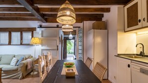 Comedor con mesa de madera, sillas, lámpara colgante y vistas al exterior.