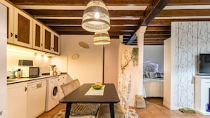 Cocina compacta con comedor, lavadora, microondas y una mesa de comedor con mantel individual.