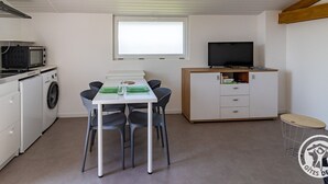 Een compacte keuken met een magnetron, wasmachine en een eethoek met een tafel en stoelen.