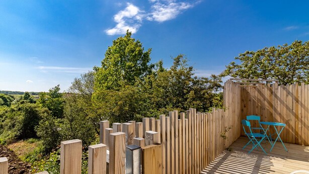 Een houten terras met een houten omheining en een blauwe stoel.