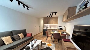 A modern living room with a sofa, coffee table, and dining area. - Renovated apartment in Méribel, near slopes, fiber included (Méribel)