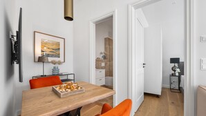 Un comedor moderno con una mesa de madera, sillas anaranjadas y un cuadro abstracto enmarcado.