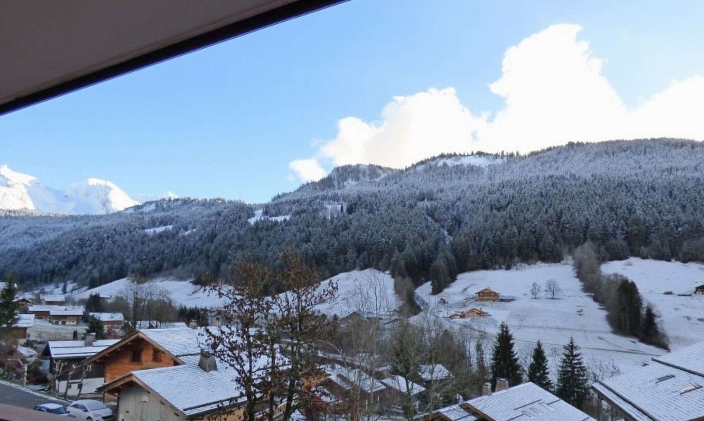 Eine verschneite Berglandschaft mit einem Dorf im Vordergrund.