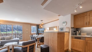 Eine moderne Küche mit Holzausstattung, ein Essbereich mit Tisch und Stühlen sowie ein großes Fenster mit Blick auf eine reizvolle Landschaft.