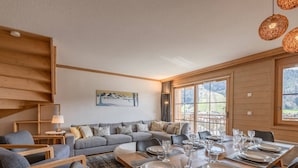 Ein stilvoller Essbereich mit einem Holztisch, gedeckt für vier Personen, umgeben von grauen Sofas und schwarzen Stühlen.