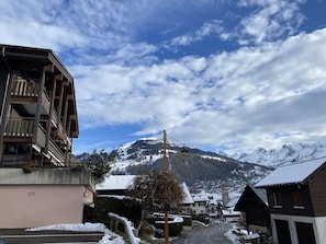 A snow-covered mountain village with a prominent building featuring balconies and a sign indicating a restaurant.