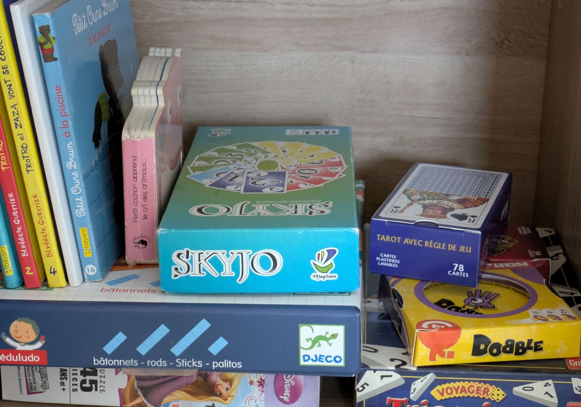 Uma seleção de jogos de tabuleiro e livros em uma estante.