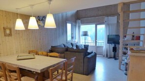 A cozy living room with a sofa, a dining table with chairs, and a television. - Charming 4-room + mezzanine for 8 people in Grand-Bornand (Le Grand-Bornand)