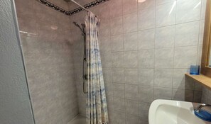 A bathroom with a shower, tiled walls, a sink, and a mirror. - Beautiful 2-room apartment in the heart of Le Grand-Bornand for 4 people (Le Grand-Bornand)