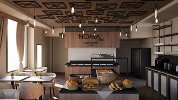 Zona de desayuno de un hotel NOMA, con un mostrador de madera que exhibe pan y pasteles, luces colgantes y un diseño moderno en el techo.