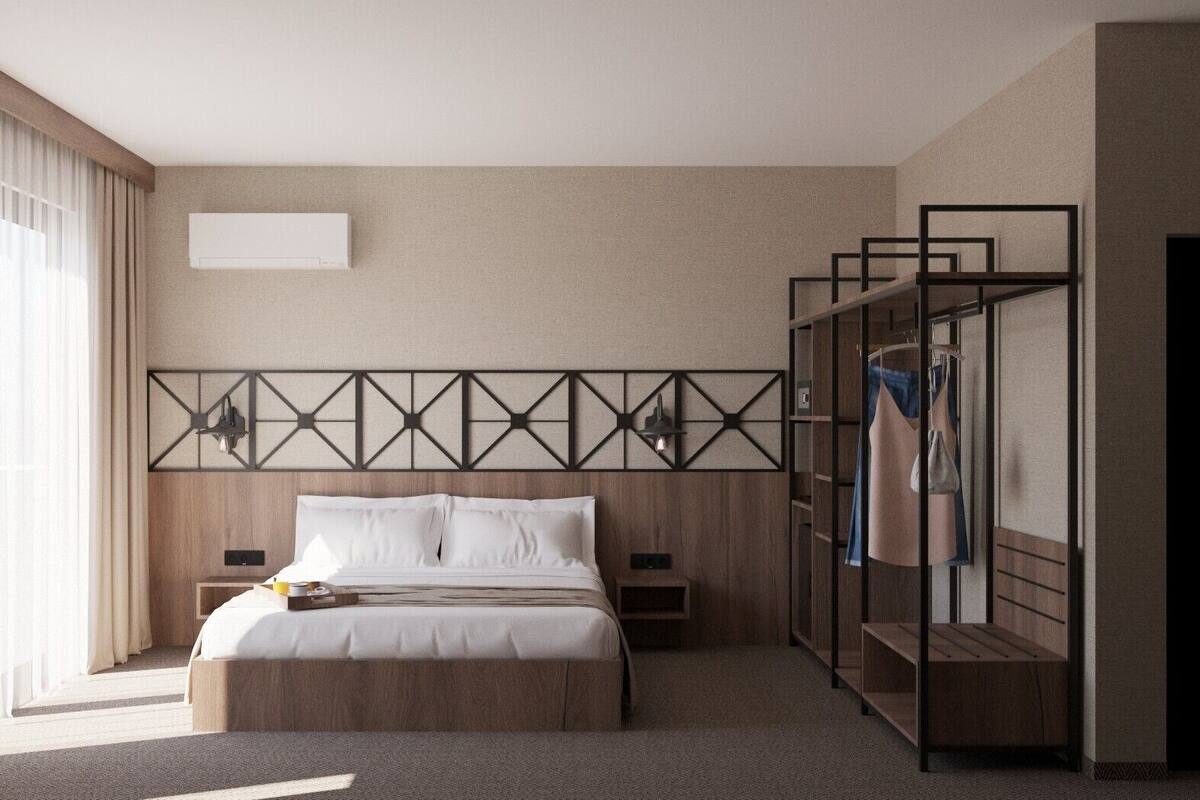 A hotel room with a large bed, two bedside tables, a wardrobe, and a headboard with geometric patterns.
