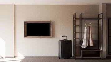 Habitación de hotel con televisión de pantalla plana en la pared, un carrito de equipaje y un armario con puerta corredera.