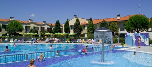 Un área de piscina con varias pistas de natación, sillas de descanso y sombrillas.