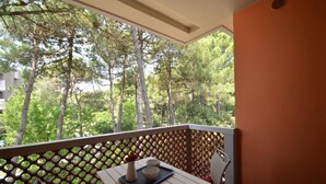 Un balcón con vistas a árboles, una mesa con una bandeja y una silla.
