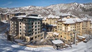A modern hotel complex with multiple buildings, a central courtyard, and a view of snow-covered mountains.