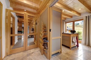 A wooden interior with a shoe rack, a view of a mountainous landscape through a window, and a door leading to another room.