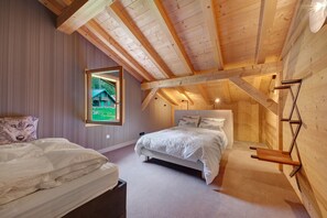 Un dormitorio con techo inclinado, una cama, un ventanal y un perchero de pared.