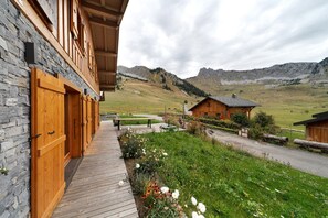 A wooden building with a stone facade, a wooden deck, and a view of a mountainous landscape. - Chalet 'Les Carroz De Mary - Sommand' with Mountain View, Private Terrace and Wi-Fi (Mieussy)