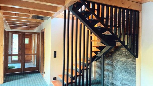 Interior de madera con una escalera y una puerta que da a otra habitación.