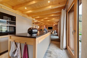 Cocina moderna con vigas de madera, una isla central y una zona de comedor con vistas.