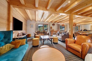 Un salón espacioso con vigas de madera, un sofá grande, una mesa de centro y un sillón de cuero.
