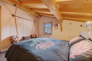 A bedroom with a bed, a hanging chair, a window, and a wooden ceiling. - Chalet 'Les Carroz De Mary - Sommand' with Mountain View, Private Terrace and Wi-Fi (Mieussy)