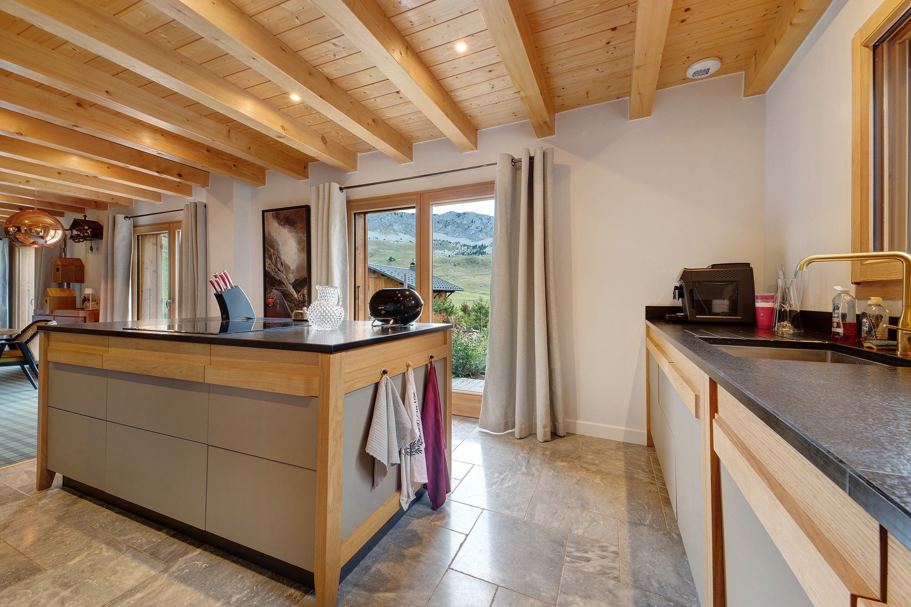 Una cocina con una isla de madera, vistas al exterior y un comedor con mesa y sillas.