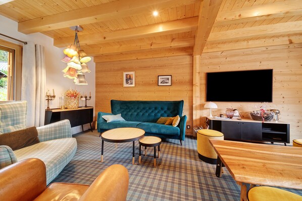 Una sala de estar acogedora con un sofá azul, una mesa de centro de madera y un televisor montado en la pared.