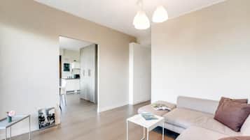 A modern living room with a sofa, a coffee table, and a dining area with a chair and a small table.