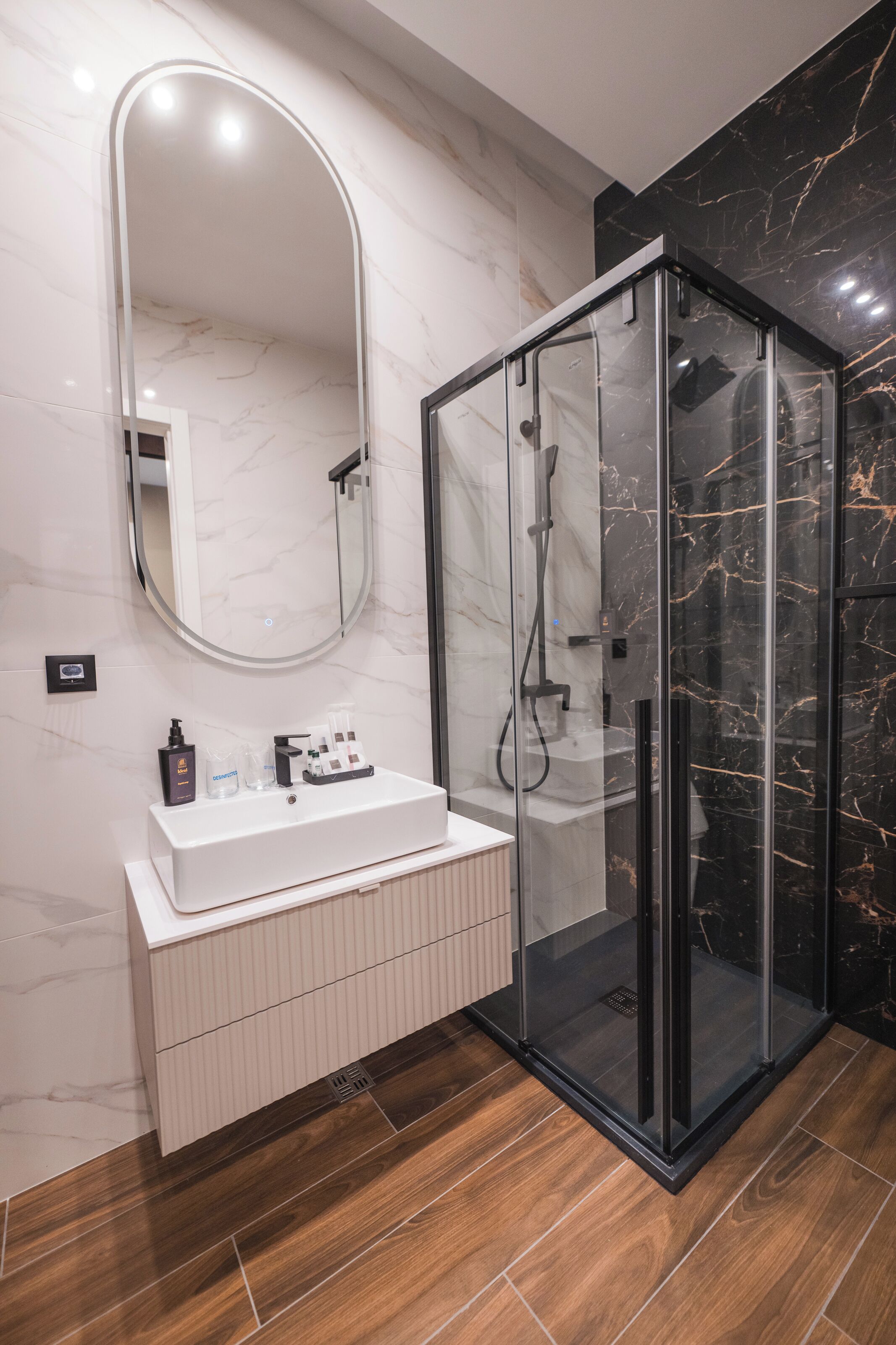A modern bathroom with a glass-enclosed shower, a white vanity, and a marble backsplash.