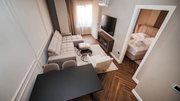 Departamento Deluxe, vista a la ciudad | Área de sala de estar | Televisión LED de 64 pulgadas con canales vía satélite