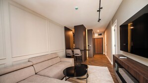 A modern living room with a sofa, a coffee table, and a TV mounted on the wall. - Ideal Apartments (Banja Luka)